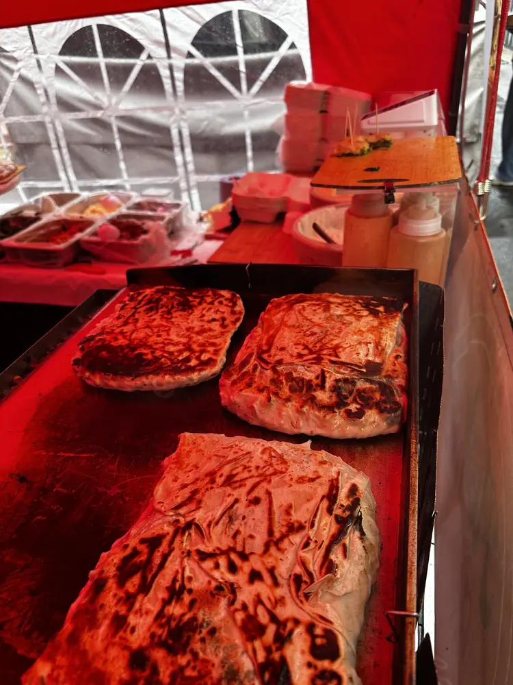 Three gozleme browning on the hot flat griddle inside the stall